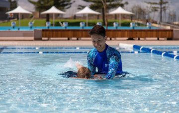 Swimming instructor helping child with swimming